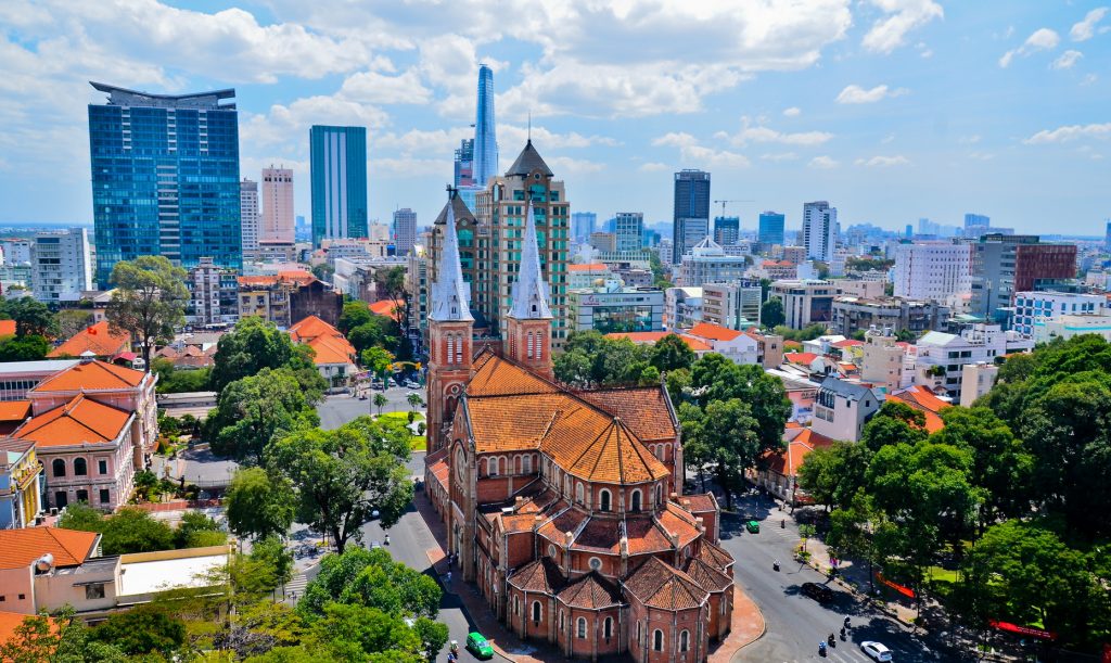 Notre Dame Cathedral in Ho Chi Minh City with modern buildings around it showing both sides of Vietnam