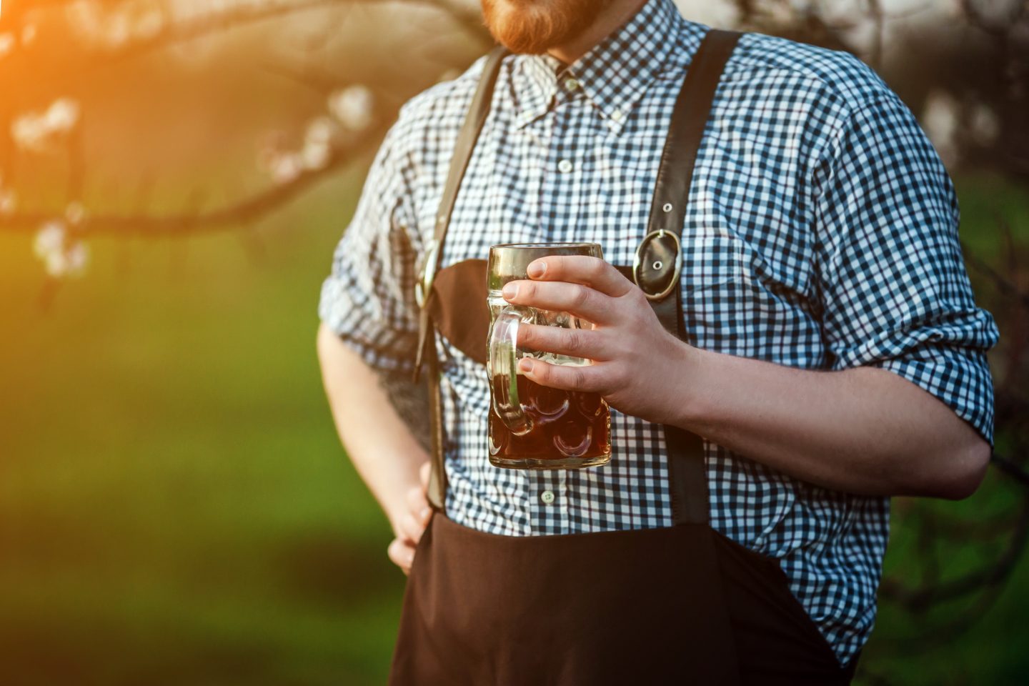 Man in Bavarian lederhosen holding a beer