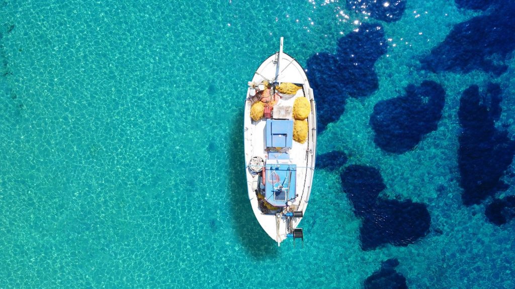 Traditional wooden fishing boat from above by the island of Mykonos in Greece