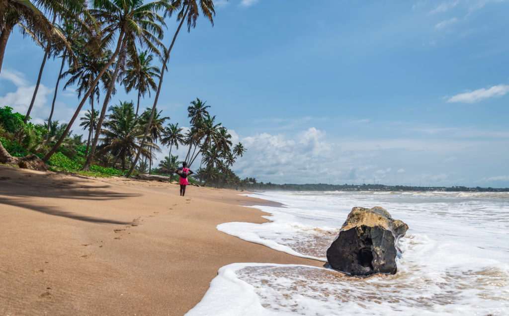 Woman walking on the beach in Axim, Ghana.