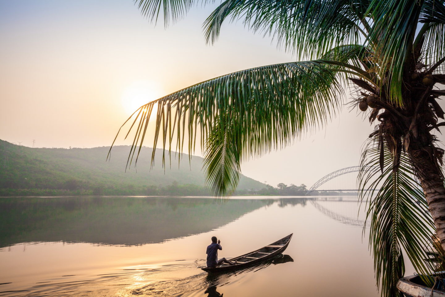 Man paddling in a traditional wooden canoe, Ghana.
